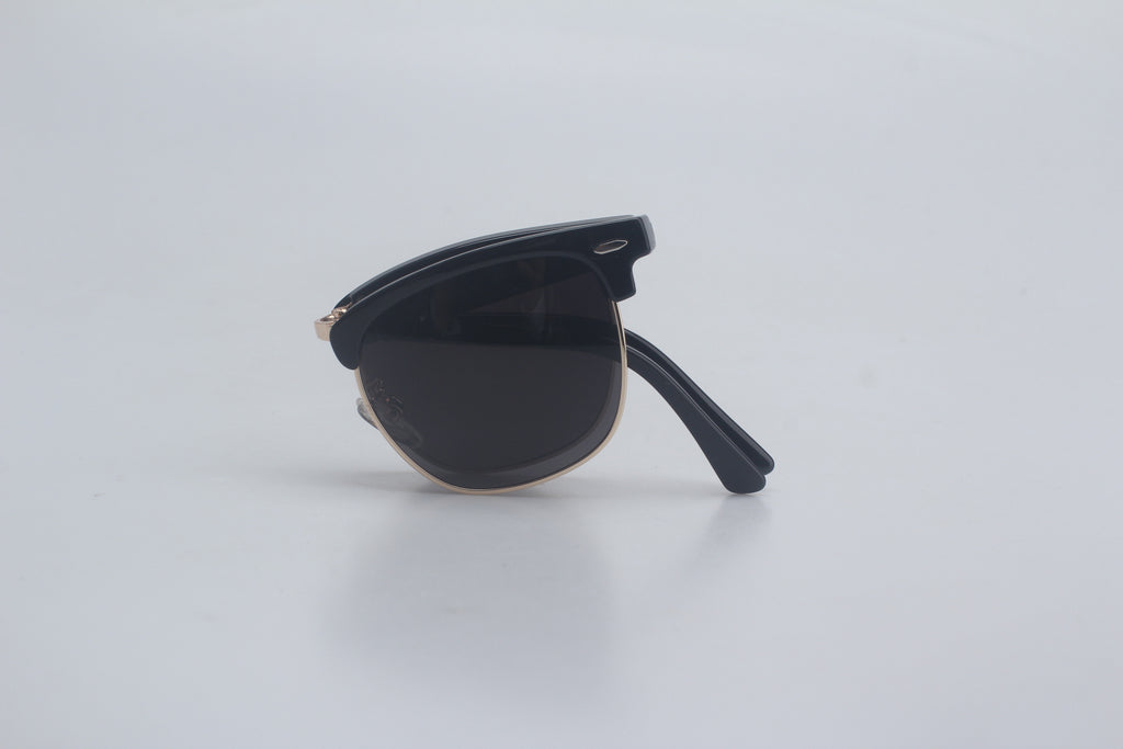 Elegant black Clubmaster sunglasses with glossy TR90 upper frames, rose gold-tone metal lower rims for a semi-rimless look, deep smoke polarized lenses offering anti-reflective clarity, displayed folded on simple white platform for versatile unisex eyewear range, chic designer sun specs, maximum UV filtering glasses, retro-modern hybrid shades, premium optic style companions, active lifestyle eye shield accessories.