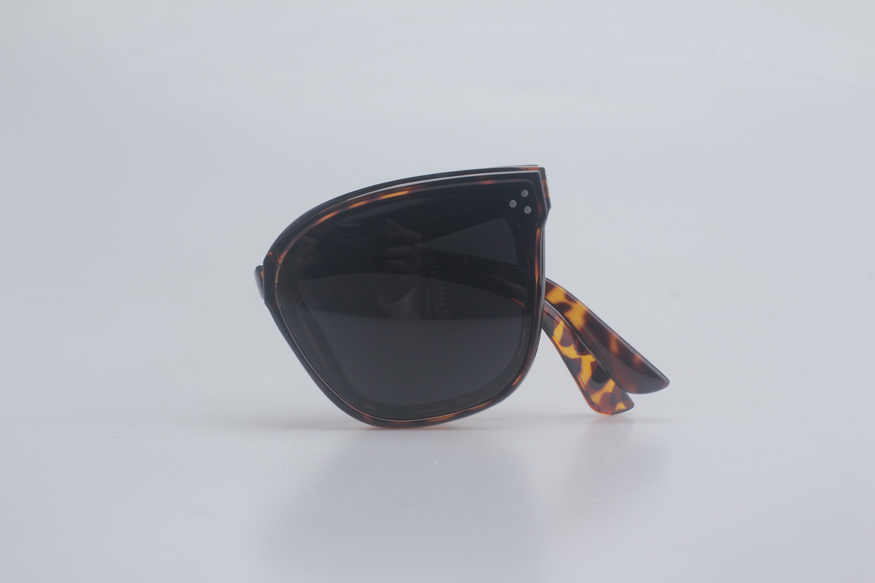 Luxury tortoiseshell aviator sunglasses featuring premium TR90 frames in mottled brown patterns, high-contrast dark polarized lenses for glare-free vision, strategically folded on crisp white canvas for upscale sunglasses inventory, sophisticated UV safeguarding eyewear, timeless rectangular style shades, elite fashion optic enhancements, versatile outdoor eye armor essentials.