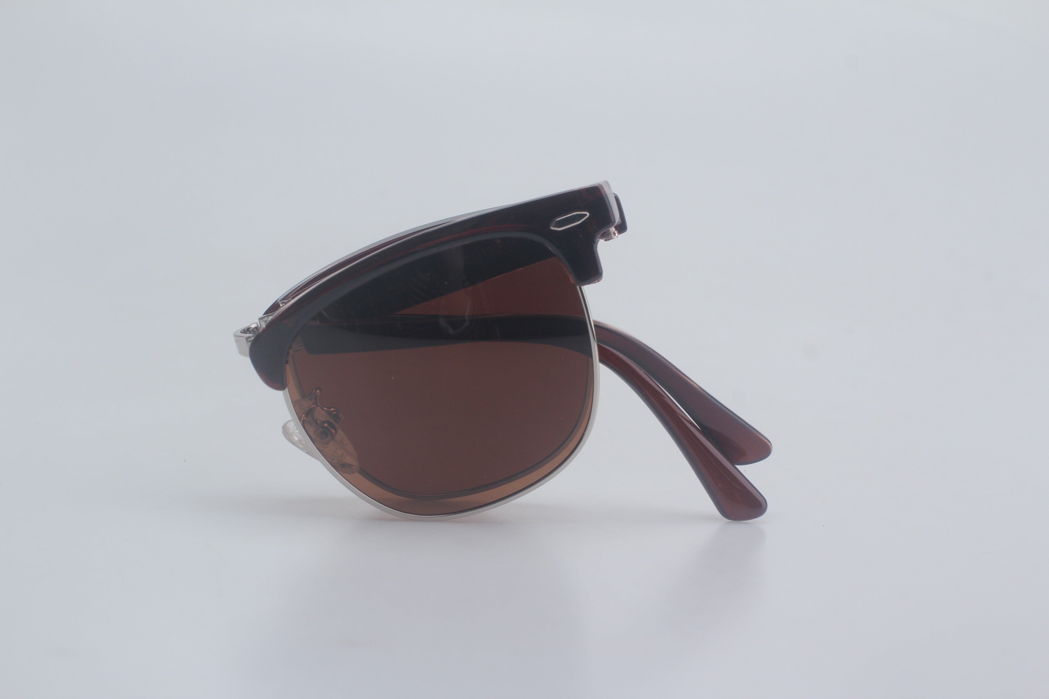 Tortoiseshell brown clubmaster sunglasses with bold TR90 browline frames, warm brown polarized lenses for superior glare control, and sleek metal accents, compactly folded on pristine white setting for sophisticated unisex optical collection, elegant designer sun eyewear, complete UVA/UVB blocking glasses, iconic mid-century inspired shades, luxury vision enhancement gear, everyday casual sun defense essentials.