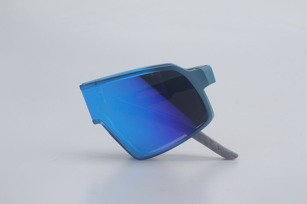 Foldable reflective wraparound sunglasses with a deep blue frame and honeycomb pattern on the legs in a neutral studio setting