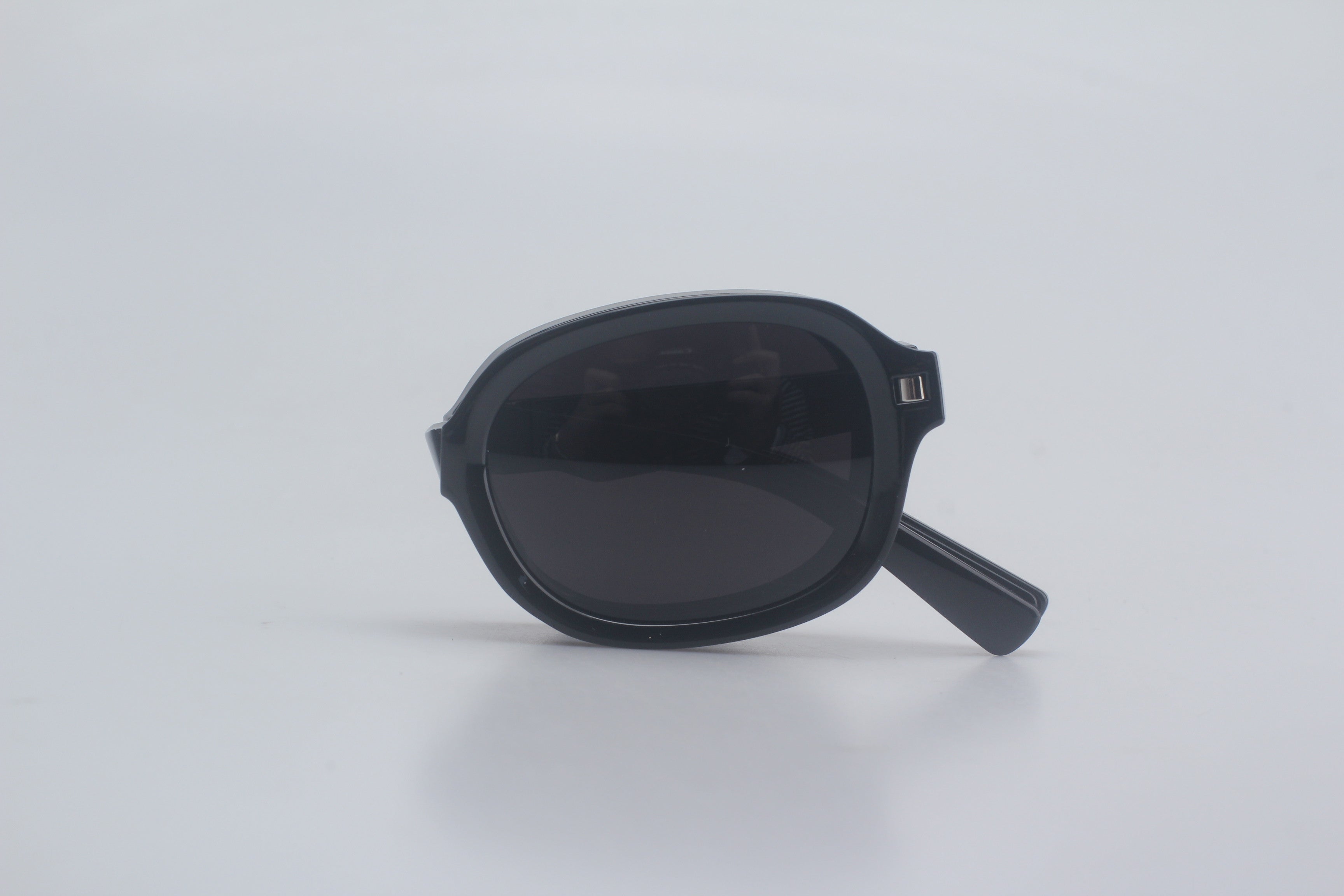 Sleek rounded rectangular sunglasses with glossy TR90 frames and deep tinted lenses, displayed folded on neutral background for premium fashion eyewear line, luxury designer eyewear, sun blocking shades, vintage-inspired sunnies, high-end vision accessories, outdoor UV defense.